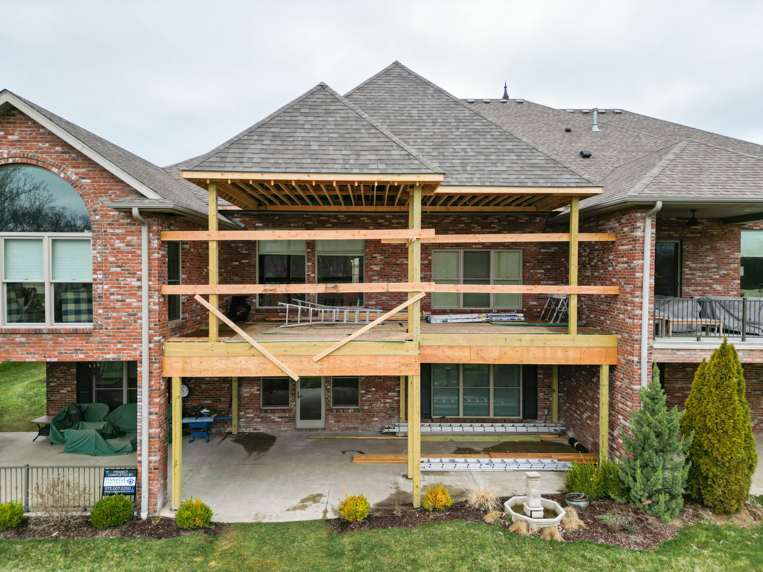 Two-story custom deck in progress on a brick home