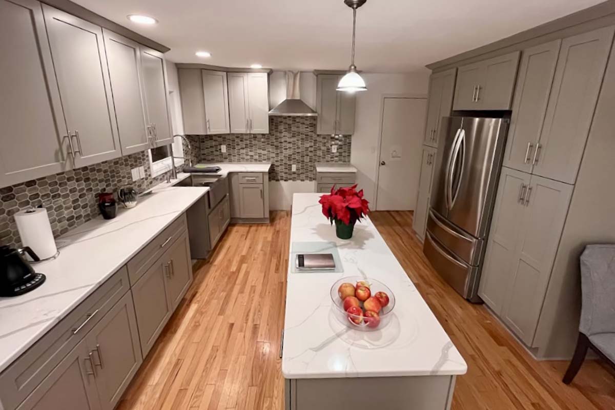After — Kitchen remodel with new gray cabinetry, quartz countertops, and tile backsplash