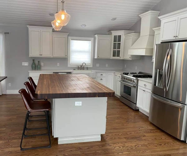 After — Kitchen remodel with white cabinets, butcher-block island, and stainless appliances